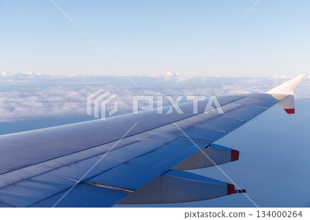 Blue sky, passenger plane wing and clouds below 134000264