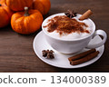 Pumpkin Spice Latte pumpkin drink topped with whipped cream sits in a white cup. Surrounding it pumpkins and cinnamon sticks creating a festive fall atmosphere. Pumpkin Spice Latte pumpkin drink topped with whipped cream sits in a white cup. Surrounding it pumpkins and cinnamon sticks creating a festive fall atmosphere. 134000389