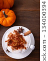 Vertical picture of tasty pumpkin spice latte with whipped cream in cup, anise and cinnamon on wooden table. Vertical picture of tasty pumpkin spice latte with whipped cream in cup, anise and cinnamon on wooden table. 134000394