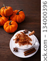 Vertical picture of tasty pumpkin spice latte with whipped cream in cup, anise and cinnamon on wooden table. Vertical picture of tasty pumpkin spice latte with whipped cream in cup, anise and cinnamon on wooden table. 134000396