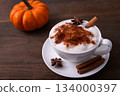 Pumpkin Spice Latte pumpkin drink topped with whipped cream sits in a white cup. Surrounding it pumpkins and cinnamon sticks creating a festive fall atmosphere. Pumpkin Spice Latte pumpkin drink topped with whipped cream sits in a white cup. Surrounding it pumpkins and cinnamon sticks creating a festive fall atmosphere. 134000397