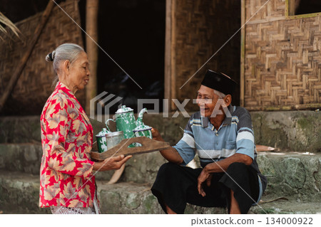 An Elderly Couple Enjoying and Sharing Traditional Tea in a Rustic and Cozy Setting An Elderly Couple Enjoying and Sharing Traditional Tea in a Rustic and Cozy Setting 134000922