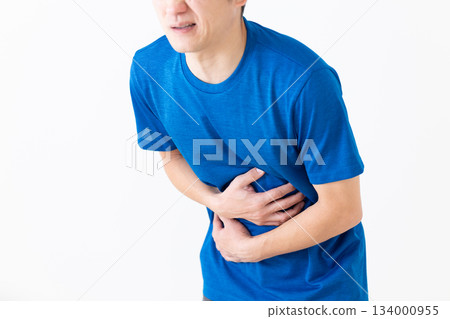 A middle-aged man wearing a T-shirt suffering from stomach pain A middle-aged man wearing a T-shirt suffering from stomach pain 134000955