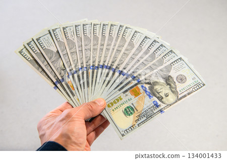 18張100美元鈔票呈扇形展開，由左手拿著，從側面拍攝。焦點清晰。 134001433