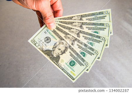 A close-up shot of five US $20 bills fanned out in the left hand and presented from the back to the front 134002287