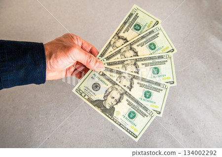 Angle shot 2 of five US $20 bills fanned out in the left hand and presented from the left 134002292