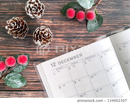 十二月計畫表和聖誕裝飾品擺放在木桌上。 134002307