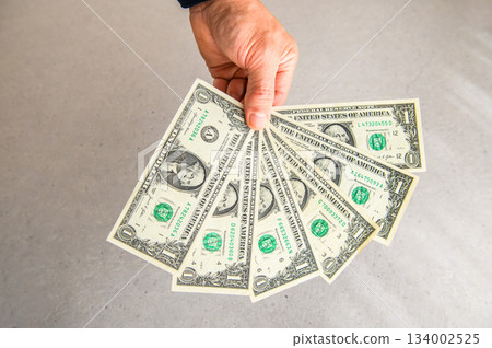 角度拍攝的第二張照片，六張一美元鈔票呈扇形展開在左手中，從背面朝前展示。 134002525
