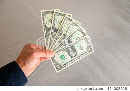 一張廣角照片,六張一美元鈔票呈扇形展開在左手中,從左前方展示。 一張廣角照片,六張一美元鈔票呈扇形展開在左手中,從左前方展示。 134002526