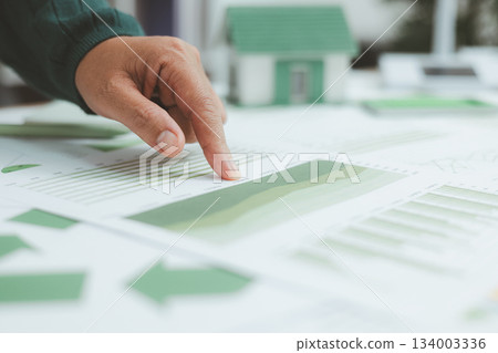 Eco-friendly business concept with hand analyzing financial charts and green earth globe symbolizing sustainable investment, environmental data analysis and green economy growth. green business. Eco-friendly business concept with hand analyzing financial charts and green earth globe symbolizing sustainable investment, environmental data analysis and green economy growth. green business. 134003336