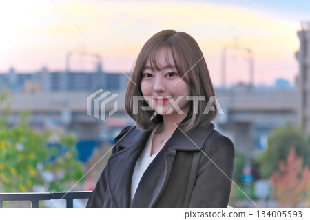 A woman looking up at the sunset on a rooftop 134005593
