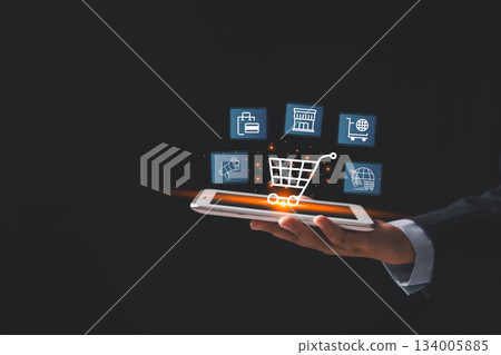 Businessman holding smartphone with glowing virtual shopping cart and ecommerce icons, representing online retail, digital purchasing, mobile commerce, modern technology solutions for business growth Businessman holding smartphone with glowing virtual shopping cart and ecommerce icons, representing online retail, digital purchasing, mobile commerce, modern technology solutions for business growth 134005885