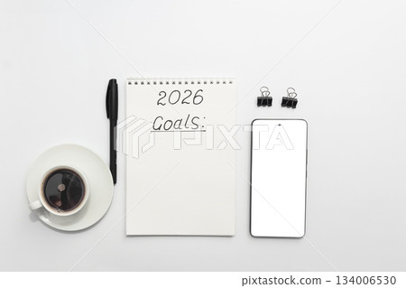 Workspace with notebook labeled 2026 Goals, pen, smartphone and coffee cup, top view, minimal and organized Workspace with notebook labeled 2026 Goals, pen, smartphone and coffee cup, top view, minimal and organized 134006530