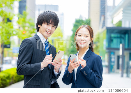 Businessman and businesswoman using smartphone Businessman and businesswoman using smartphone 134006604