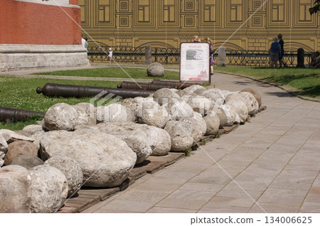The photograph depicts antique cannons positioned on a green lawn. Next to the cannons is an information board with an image and text, likely explaining the history of these weapons. In the distance,  134006625