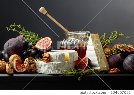 Soft cheeses with fruits on a black background. 134007031