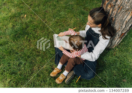 Mother and Toddler Drawing Together in a Summer Park. Parenting and Childhood Development Concept Mother and Toddler Drawing Together in a Summer Park. Parenting and Childhood Development Concept 134007289