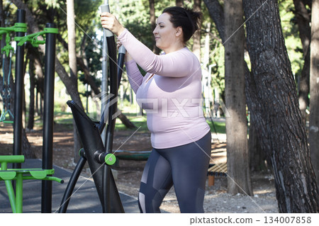 an adult woman doing stretching exercises outside in green park, mental setting training an adult woman doing stretching exercises outside in green park, mental setting training 134007858