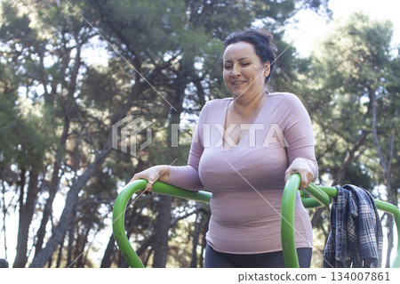 an adult woman doing stretching exercises outside in green park, mental setting training an adult woman doing stretching exercises outside in green park, mental setting training 134007861