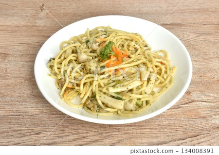 spicy stir fried spaghetti with scallop in garlic butter sauce topping shrimp egg on plate  134008391