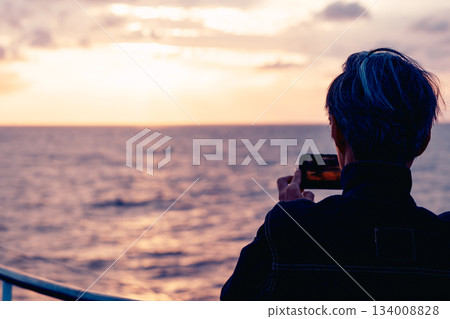 Back view of a senior man taking pictures of the sunset Back view of a senior man taking pictures of the sunset 134008828