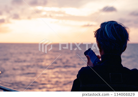 Back view of a senior man taking pictures of the sunset Back view of a senior man taking pictures of the sunset 134008829
