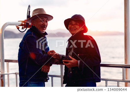 夕陽西下，一對老年夫婦在船上擁抱在一起的肖像。 134009044