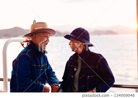 夕陽西下，一對老年夫婦在船上擁抱在一起的肖像。 134009046
