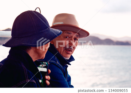 夕陽西下，一對老年夫婦在船上擁抱在一起的肖像。 134009055