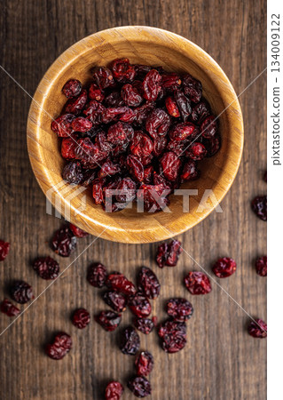 Tasty dried cranberries in bowl on wooden table. Top view. Tasty dried cranberries in bowl on wooden table. Top view. 134009122