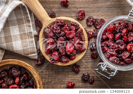 Tasty dried cranberries on wooden spoon on wooden table. Top view. Tasty dried cranberries on wooden spoon on wooden table. Top view. 134009123
