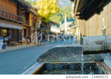 妻籠宿的竹製飲水處,背景是秋日的街景 妻籠宿的竹製飲水處,背景是秋日的街景 134009172