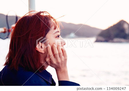 一位二十多歲的女子背對著鏡頭,凝望日落時的大海。 一位二十多歲的女子背對著鏡頭,凝望日落時的大海。 134009247