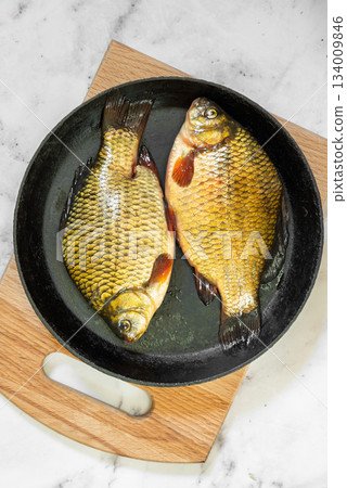 The fish are golden with distinct scales and fins, ready for cooking 134009846