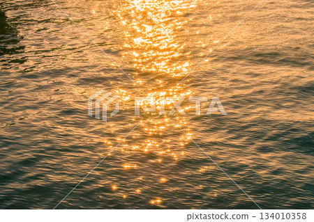 Reflection of golden sunlight on water. Sunset sea view with sparkle sunlight. Sunset light hitting on the ocean. Sunset sea background. Reflection of golden sunlight on water. Sunset sea view with sparkle sunlight. Sunset light hitting on the ocean. Sunset sea background. 134010358