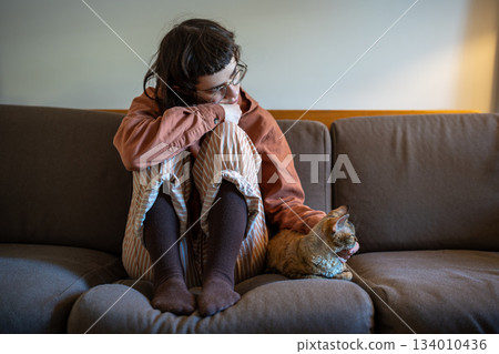 Lonely pet owner girl in need of comfort, emotional support, empathy sitting at home, stroking cat Lonely pet owner girl in need of comfort, emotional support, empathy sitting at home, stroking cat 134010436