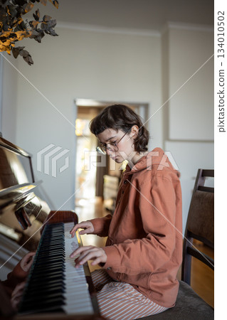 Girl student pianist practicing music skills playing piano at home, pumps up your piano skills 134010502
