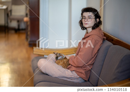 Tired pensive teenage girl petting pet cat taking break looking side sitting on couch at home. Tired pensive teenage girl petting pet cat taking break looking side sitting on couch at home. 134010518
