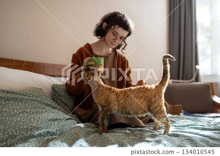 Cat begging attention and food petting of teen girl owner hand in bed at home. Cat begging attention and food petting of teen girl owner hand in bed at home. 134010545
