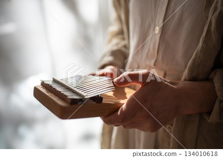 Kalimba ethnic musical instrument. Hands playing relaxation melody on metal keys, producing sounds. Kalimba ethnic musical instrument. Hands playing relaxation melody on metal keys, producing sounds. 134010618