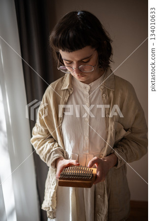 Teenager improvising on ethnic percussion instrument kalimba. Sound therapy, melody meditation 134010633