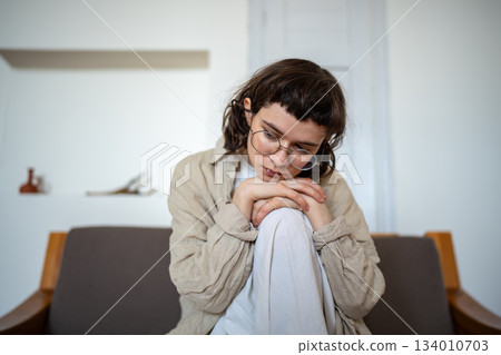 Depressed tired lonely desperate teen girl sadly sitting on couch at home feeling sorrow, solitude Depressed tired lonely desperate teen girl sadly sitting on couch at home feeling sorrow, solitude 134010703