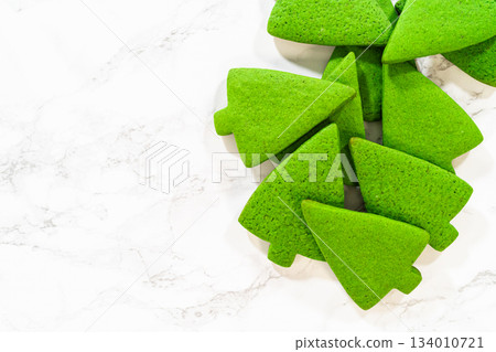 A pile of Green Gingerbread Cookies shaped like Christmas trees, layered together to showcase their festive design and vibrant green color. A pile of Green Gingerbread Cookies shaped like Christmas trees, layered together to showcase their festive design and vibrant green color. 134010721