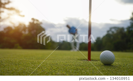 Golf ball is on a green lawn in a beautiful golf course with morning sunshine. Golf ball is on a green lawn in a beautiful golf course with morning sunshine. 134010951