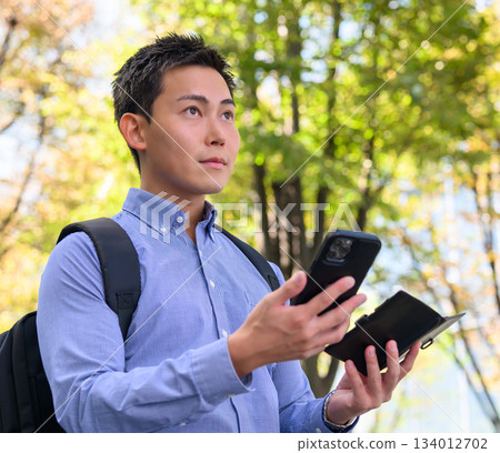 Salesman operating a smartphone outdoors 134012702