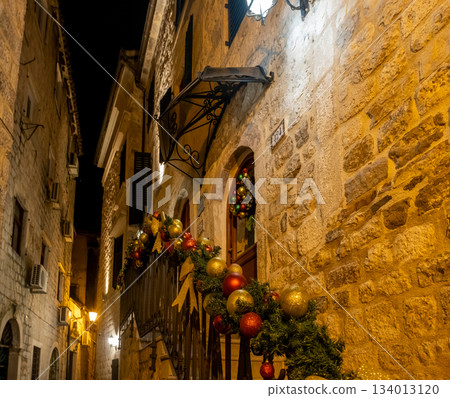 Festive Christmas garland with red and gold ornament adorning building balcony in Kotor 134013120