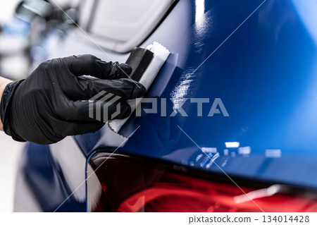 Ceramic coating application on blue car body near taillight during professional car detailing process Ceramic coating application on blue car body near taillight during professional car detailing process 134014428
