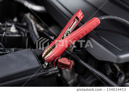 Car battery charging with jumper cables in vehicle engine bay during emergency power boost Car battery charging with jumper cables in vehicle engine bay during emergency power boost 134014453