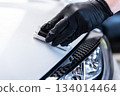 Ceramic coating application on car body near headlight during professional car detailing process 134014464