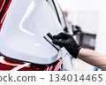Ceramic coating application on rear car body panel near taillight during professional car detailing 134014465